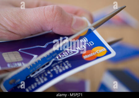 Un primo piano di una donna il taglio di una carta di credito - debito della carta di credito concetto Foto Stock