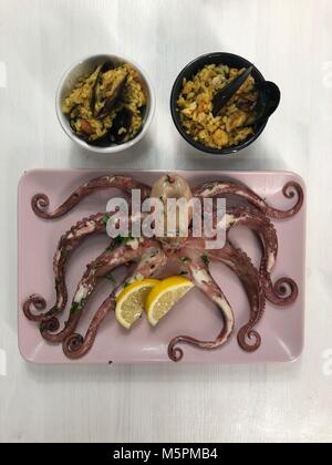 Pesce fritto,di riso con le cozze e il polpo sul piatto con limone e insalata. Foto Stock