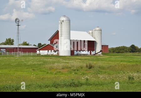 Fienile silo e circondato da lussureggianti terreni agricoli raccolti su un luminoso giorno di estate Foto Stock