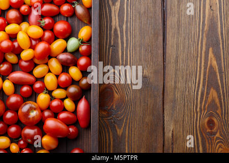 Vassoio in legno colorato e i pomodori ciliegia mix su tavole di legno sfondo Foto Stock