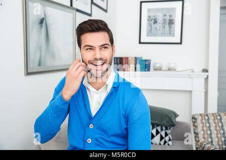 Giovane uomo paziente attesa sessione psicologia parlando utilizza lo smartphone Foto Stock