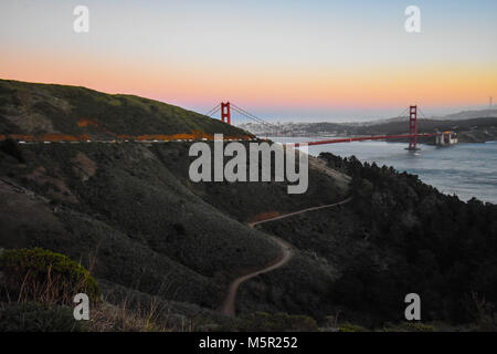Il sole al tramonto proietta un bagliore sognante su San Francisco e il Golden Gate. Foto Stock