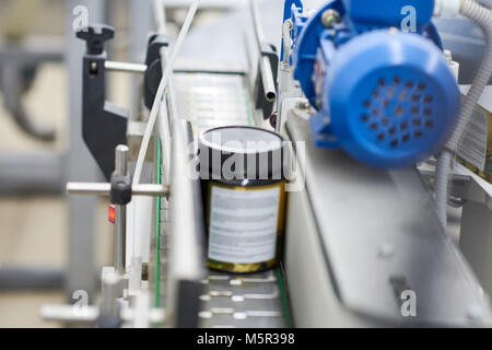 Close-up shot di pillola bottiglia in movimento lungo la linea di trasporto della moderna fabbrica farmaceutica, sfondo sfocato Foto Stock