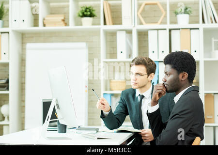 Riunione di lavoro dei programmatori di talento: essi si radunarono in ufficio open space e un po' di brainstorming su start-up, uno di loro prendere note Foto Stock