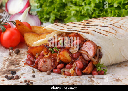 Shawarma originale con fagioli e salsicce. Still-life su uno sfondo di legno. Foto Stock