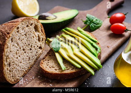 Avocado e pane di segale tostato sul bordo di taglio. Primo piano Foto Stock