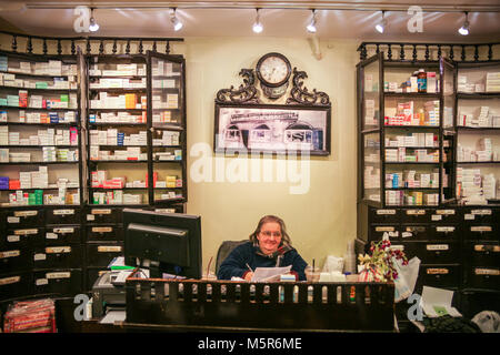 Un farmacista seduto alla sua scrivania in una delle più antiche farmacie della città vecchia di Corfù, Grecia Foto Stock