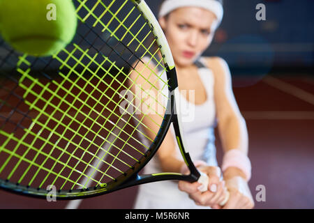 Ritratto di donna forte giocando a tennis nella corte interna, concentrarsi sulla racchetta da tennis di colpire la sfera, spazio di copia Foto Stock