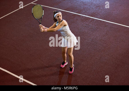 Angolo alto ritratto di donna forte giocando a tennis nella corte interna racchetta oscillante, spazio di copia Foto Stock