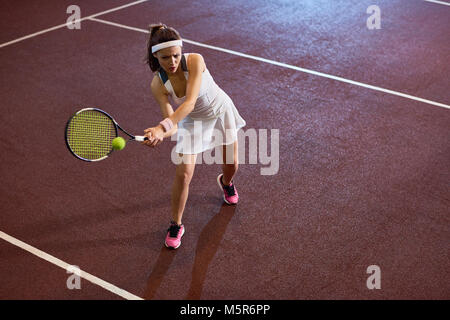 Angolo alto a piena lunghezza ritratto di donna forte giocando a tennis nella corte interna, spazio di copia Foto Stock