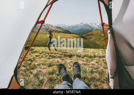 Camping giovane viaggiare vista dalla tenda ingresso donna a camminare in montagna uomo piedi rilassante all'interno del concetto di stile di vita avventura vacanze estive outd Foto Stock