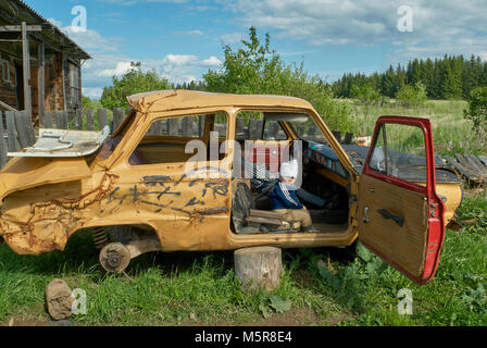 Due bambini di giocare con il relitto della vettura, Russia, regione di Perm. Foto Stock