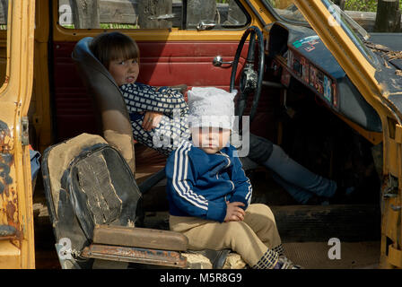 Due bambini di giocare con il relitto della vettura, Russia, regione di Perm. Foto Stock