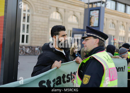 Mannheim, Germania. Il 25 febbraio, 2018. Un funzionario di polizia parla di un manifestante curdo, cercando di convincerlo a terminare la protesta. Turchi e curdi manifestanti di fronte gli uni degli altri in occasione delle proteste nel centro della città di Mannheim. Il bagno turco manifestanti hanno sostenuto l'attacco da parte dell'esercito turco sulla città siriana di Afrin, il quale è controllato dal popolare curda Unità di Protezione (YPG). Il contatore curda manifestanti hanno chiesto lo stato turco i terroristi per l'attacco. Credito: Michael Debets/Pacific Press/Alamy Live News Foto Stock