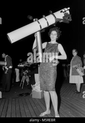 Una donna forte hefts un telescopio riflettore, ca. 1961. Foto Stock