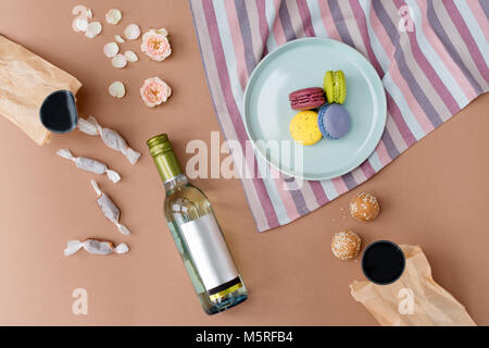 Amaretti colorati con caramelle fatte a mano, vino bianco e rose. Il francese macaron torte. Dolci con fiori, laici piana. Foto Stock