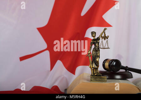 Statua di Themis e giudice di martello su un libro. Bandiera del Canada in background. Primo piano Foto Stock