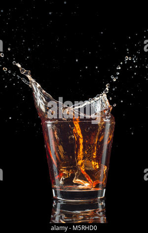 Bicchiere di whiskey con splash isolati su sfondo nero. Foto Stock