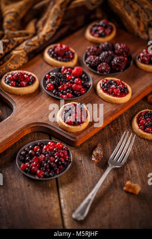 Deliziosi frutti mini crostate (pasticcini) su sfondo di legno Foto Stock