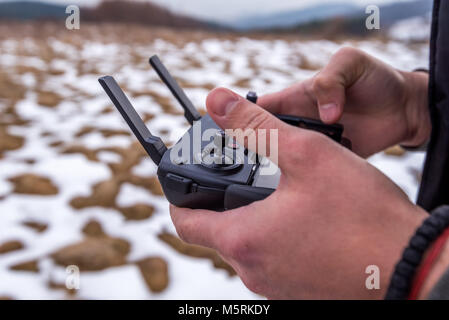 L'uomo battenti un drone in città utilizzando un controllore d'inverno. Foto Stock