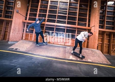 Due giovani pattinatori sono la pratica con il loro skateboard in un pattino indoor hall. Foto Stock