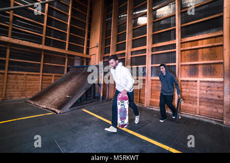 Due giovani pattinatori sono la pratica con il loro skateboard in un pattino indoor hall. Foto Stock