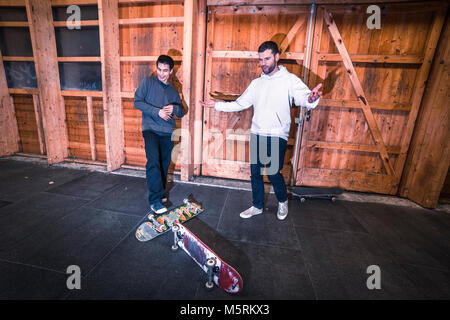 Due giovani pattinatori sono la pratica con il loro skateboard in un pattino indoor hall. Foto Stock