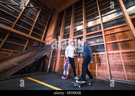 Due giovani pattinatori sono la pratica con il loro skateboard in un pattino indoor hall. Foto Stock