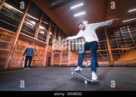 Due giovani pattinatori sono la pratica con il loro skateboard in un pattino indoor hall. Foto Stock