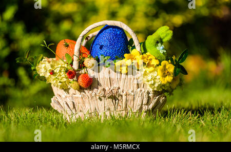 Carrello con i tradizionali simboli pasquali: uova colorate, bunny, fiori e frutti di bosco Foto Stock