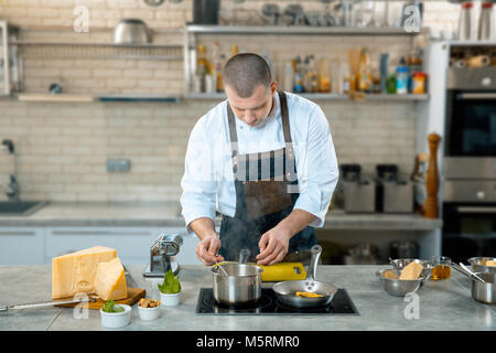 Lo chef in un processo - preparazione piatto italiano. Cucina interier Foto Stock