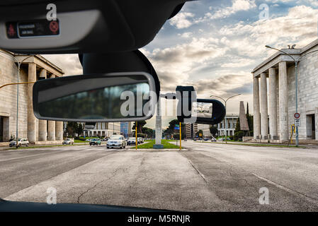 Guardando attraverso un auto dashcam telecamera installata su di un parabrezza con vista della pittoresca architettura neoclassica nel quartiere EUR di Roma, Italia Foto Stock