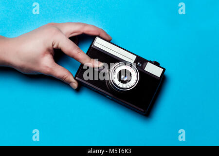 Vecchia macchina fotografica su uno sfondo blu, la mano preme l'otturatore Foto Stock