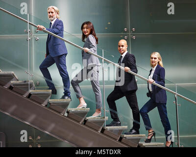 Multinazionale e multietnica corporate business persone schierate sulle scale di un ufficio moderno edificio guardando la telecamera sorridendo. Foto Stock