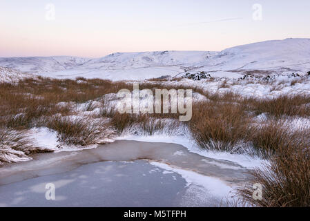 Nevoso inverno mattina nelle colline del Peak District. Un pool di congelati a sud di testa, Hayfield con vista al Kinder Scout. Foto Stock