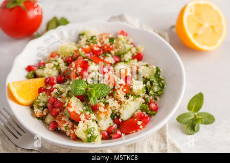 Tabulé con insalata di pomodoro, cetriolo, cuscus, menta e melograno. Tradizionale medio orientale o piatto arabo. Foto Stock