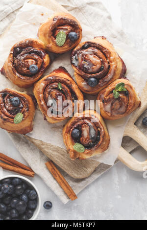 In casa ciambelle alla cannella con mirtilli e cannella su una tavola di legno Foto Stock