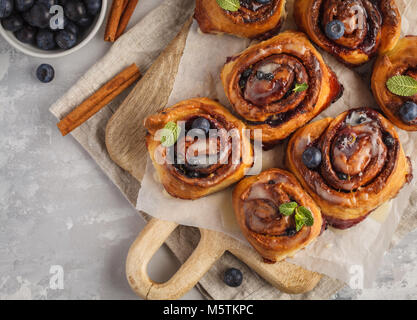 In casa ciambelle alla cannella con mirtilli e cannella su una tavola di legno Foto Stock