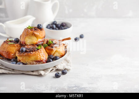 In casa ciambelle alla cannella con mirtilli e cannella su lastra grigia, sfondo prima colazione Foto Stock