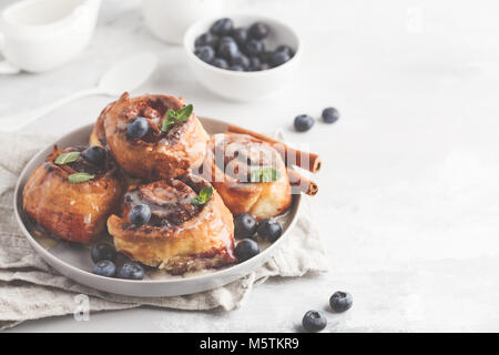 In casa ciambelle alla cannella con mirtilli e cannella su lastra grigia, sfondo prima colazione Foto Stock