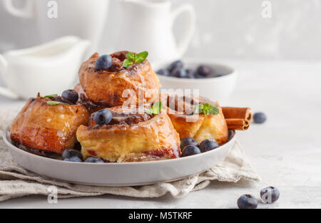 In casa ciambelle alla cannella con mirtilli e cannella su lastra grigia, sfondo prima colazione Foto Stock