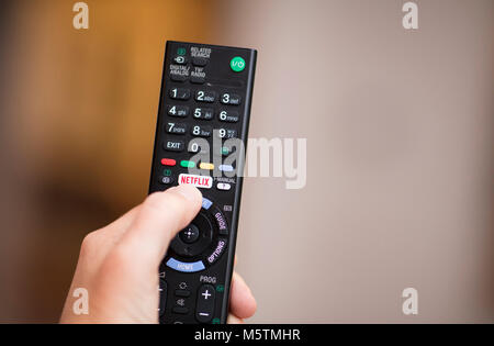 Una persona che utilizza il telecomando della televisione con un apposito logo di Netflix sul pulsante - Febbraio 2018 Foto Stock