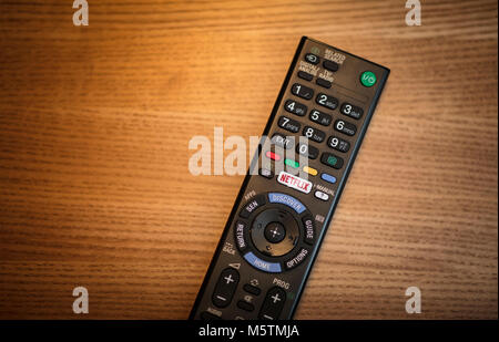 Una persona che utilizza il telecomando della televisione con un apposito logo di Netflix sul pulsante - Febbraio 2018 Foto Stock