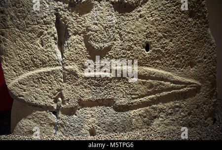 Close up di un tardo Neolitico europeo Menhir preistorici di pietra permanente con intagli sulla sua faccia laterale. In fondo è una scultura di un pugnale in esecuzione Foto Stock