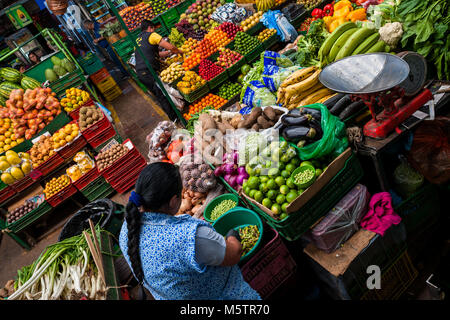 Un fornitore colombiano salta fuori i piselli in una ciotola al mercato di Paloquemao di Bogotá, in Colombia. Foto Stock