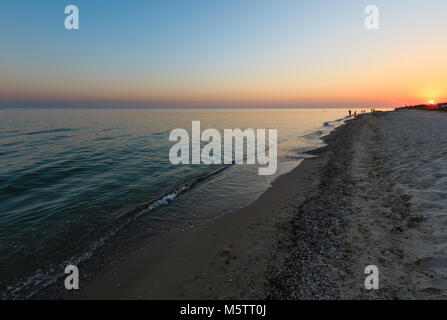 Sole al tramonto sopra autosufficienti camping nella prateria di sabbia sul mare Azov arenile (Lazurne, Regione di Kherson, Ucraina). Persone irriconoscibile. Foto Stock