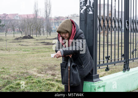Una donna anziana chiede elemosina vicino al mercato agricolo nella città di Tiraspol, il centro della repubblica non riconosciuta di Transnistria Foto Stock