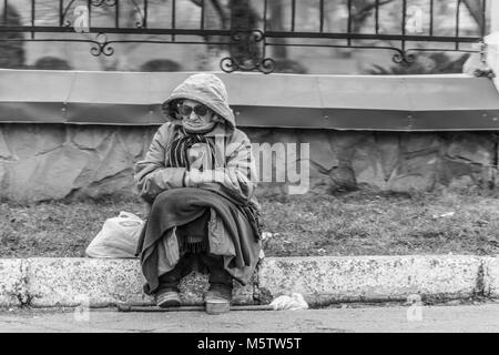 Una vecchia donna supplica per la ALMS dalla strada. Foto in bianco e nero. Foto Stock