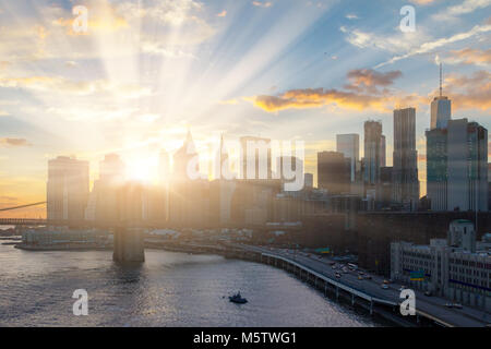 La luce del sole splende dietro New York skyline della città Foto Stock