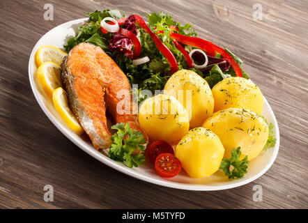 Salmone fritto e verdure sul tavolo di legno Foto Stock